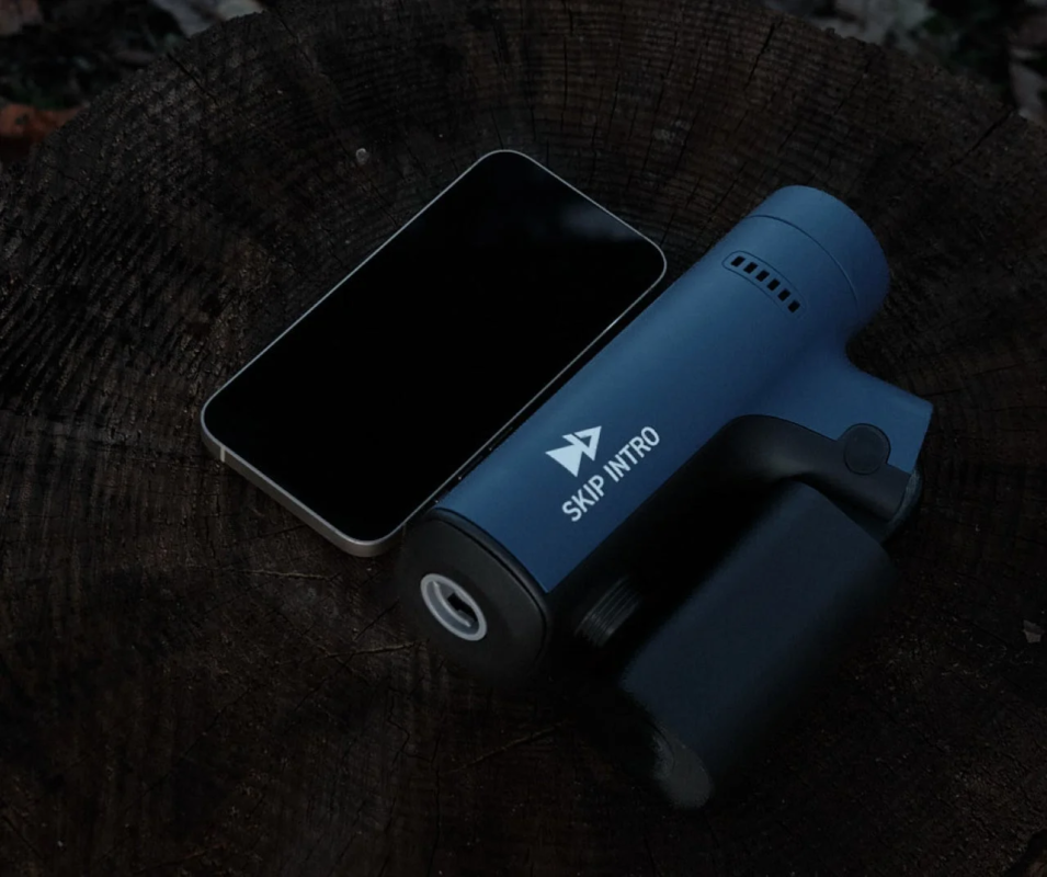 暗い木製の切り株の上に、スマートフォンと青いガジェットが置かれている