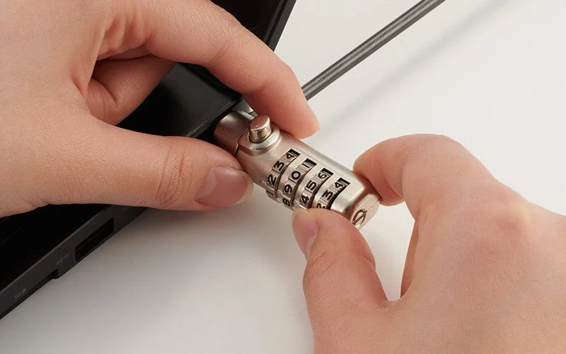 ノートパソコンに盗難防止用のダイヤル式ワイヤーロックを取り付けている様子