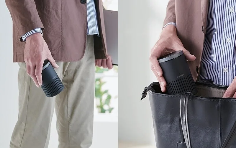 男性が黒い円筒形のポータブルデバイスを手に持ち、その後、黒いビジネスバッグに収納している様子