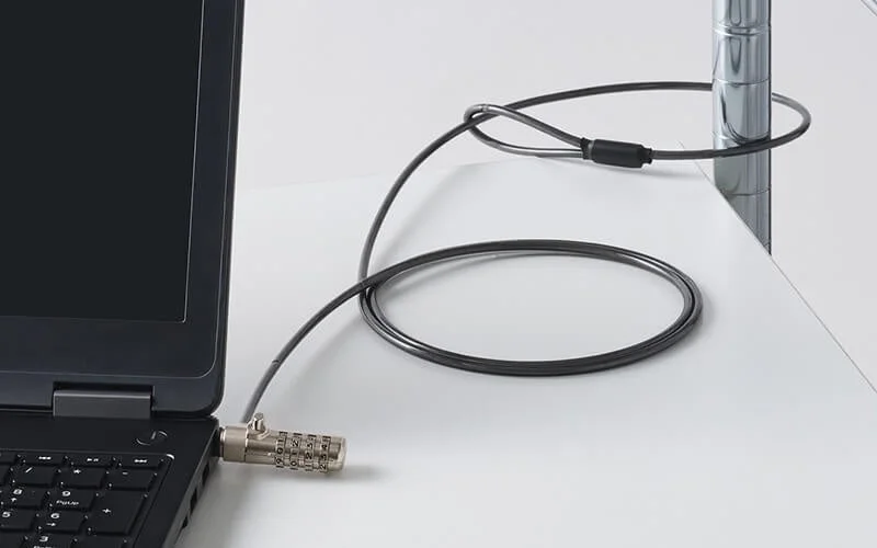 黒いノートパソコンがダイヤル式セキュリティワイヤーロックで金属製の柱に固定されている様子