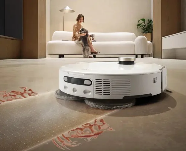 リビングで床を清掃するロボット掃除機と女性、犬