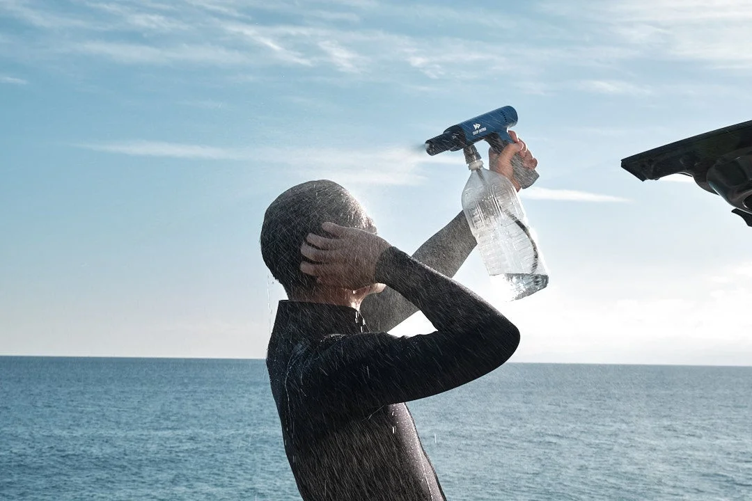 ウェットスーツを着た人がシャワーで体を洗い流す様子