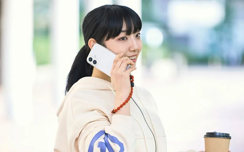 ポニーテールの若い女性が笑顔でスマートフォンで通話