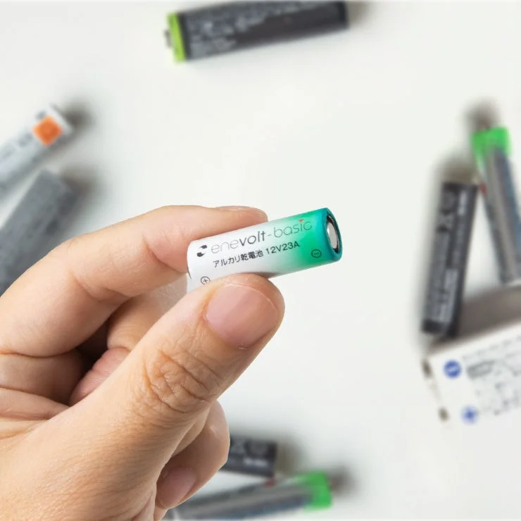 手がアルカリ乾電池 12V23Aをつまむ様子