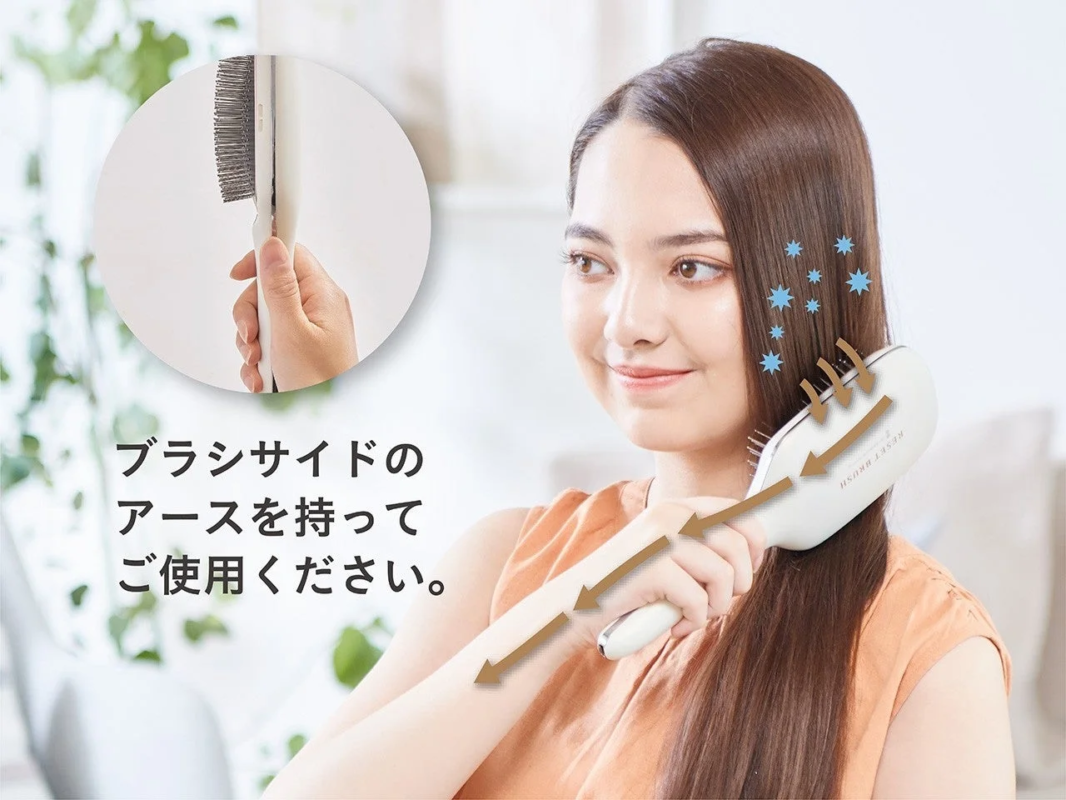 女性が白いヘアブラシで髪をとかしている画像。ブラシサイドのアースを持って使用するよう指示されており、髪のまとまりや静電気抑制効果が期待できるヘアケア製品の紹介です。