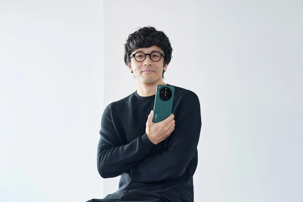 眼鏡をかけたコハラタケル氏とXiaomiスマートフォン