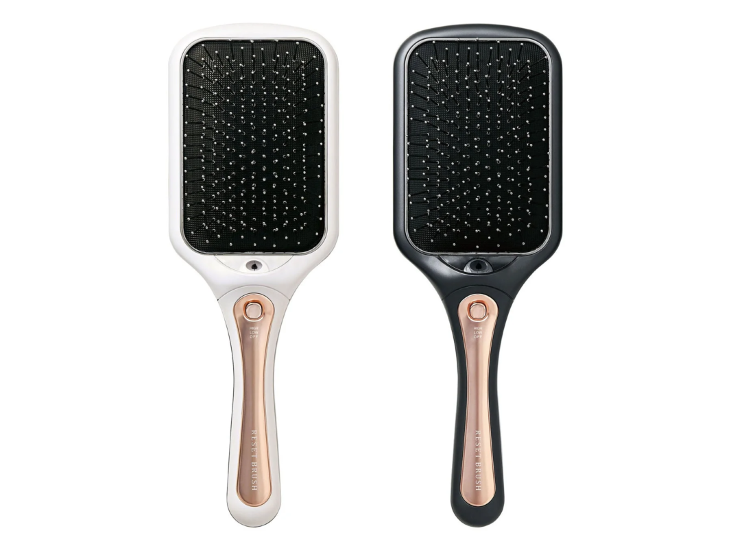 白と黒の2種類の電動ヘアブラシが並んでいます。持ち手部分にはローズゴールドのアクセントがあり、「RESET BRUSH」と表示。HIGH/LOW/OFFの切り替えボタンも確認できます。頭皮ケアやヘアスタイリングに使う美容家電です。