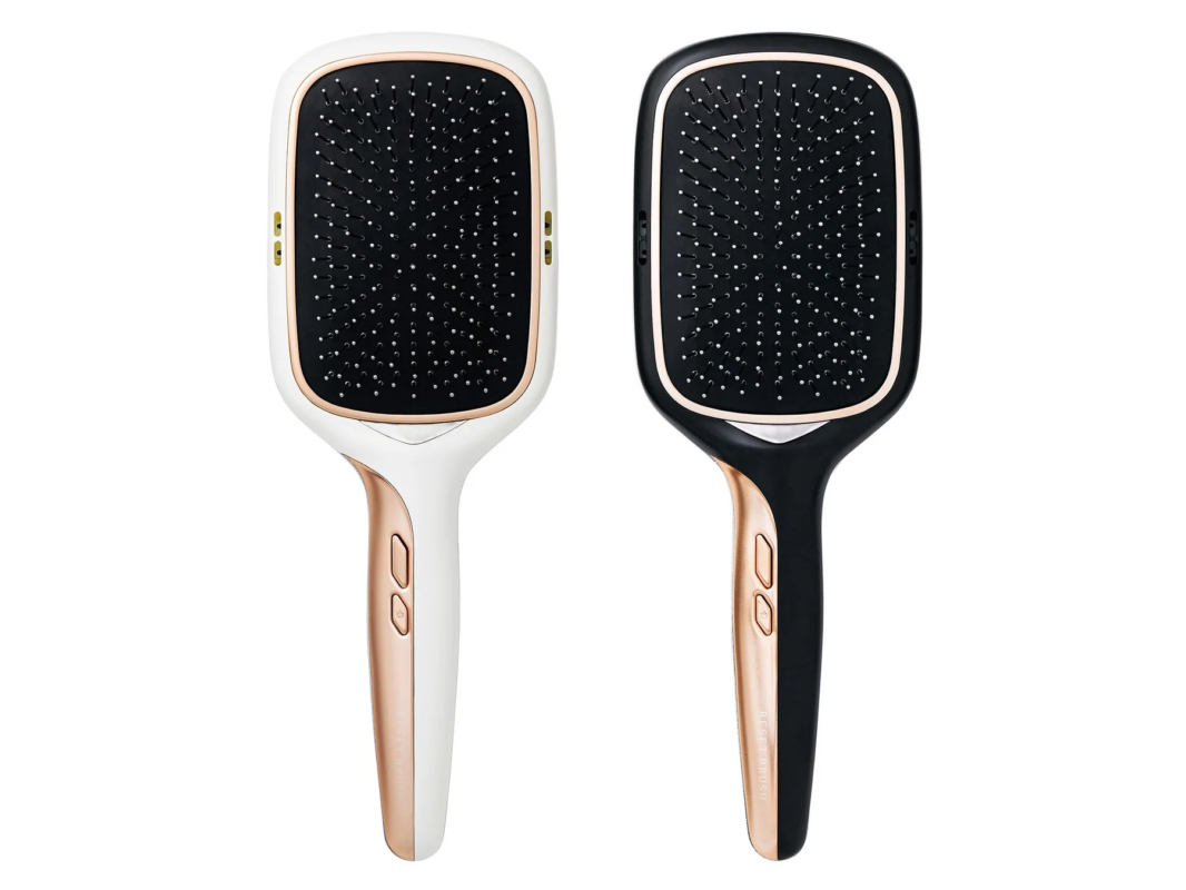 白と黒の2色のヘアブラシが並べられた画像です。どちらもローズゴールドのアクセントがあり、ハンドル部分には「RESET BRUSH」の文字とボタンが見えます。髪のブラッシングやケアに使う美容家電と考えられます。