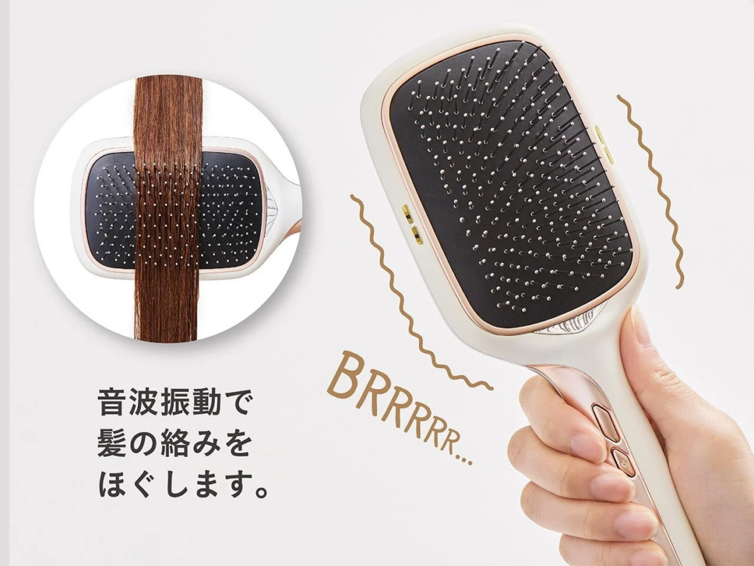 音波振動で髪の絡みを優しくほぐすヘアブラシの広告画像です。白い本体とローズゴールドのアクセントが特徴で、実際に髪をとかしている様子や、振動している様子が示されています。