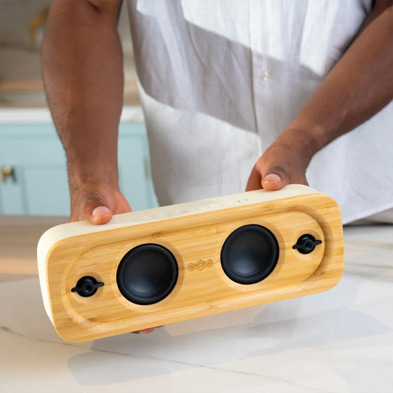 男性が竹製のスタイリッシュなポータブルスピーカーを両手で持っている画像です。リビングやキッチンで音楽を楽しむ、エコフレンドリーなライフスタイルを提案しています。
