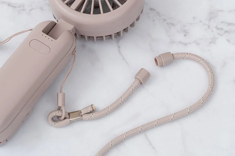 淡いピンク色の携帯扇風機と、それに取り付けるストラップの一部