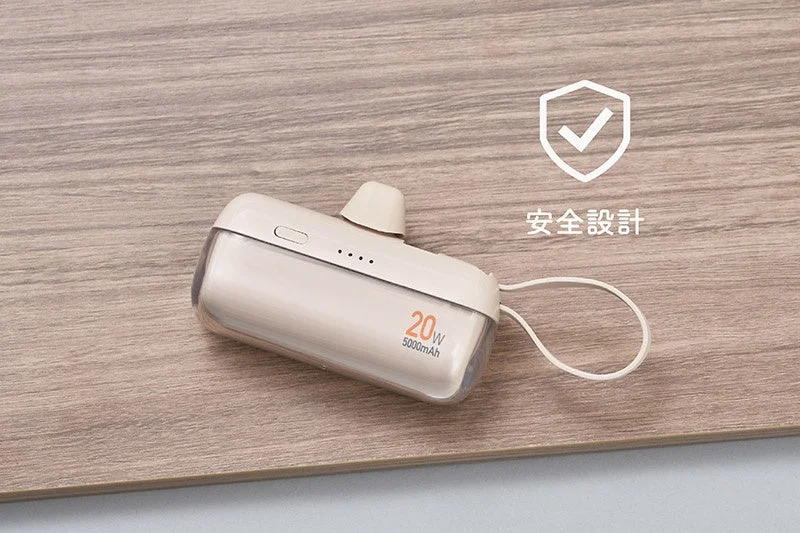 ベージュ色のコンパクトなモバイルバッテリーが木目調の背景に置かれています