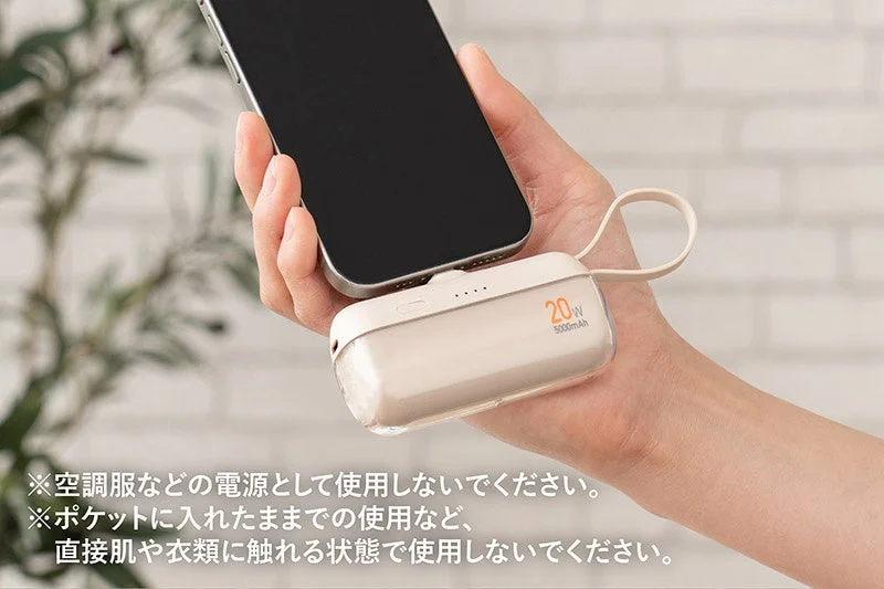 手のひらに収まるサイズのモバイルバッテリーでスマートフォンを充電している様子