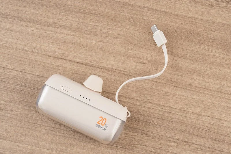 木目調のテーブルに置かれた白いポータブル充電器で、USB-Cケーブルが接続されています