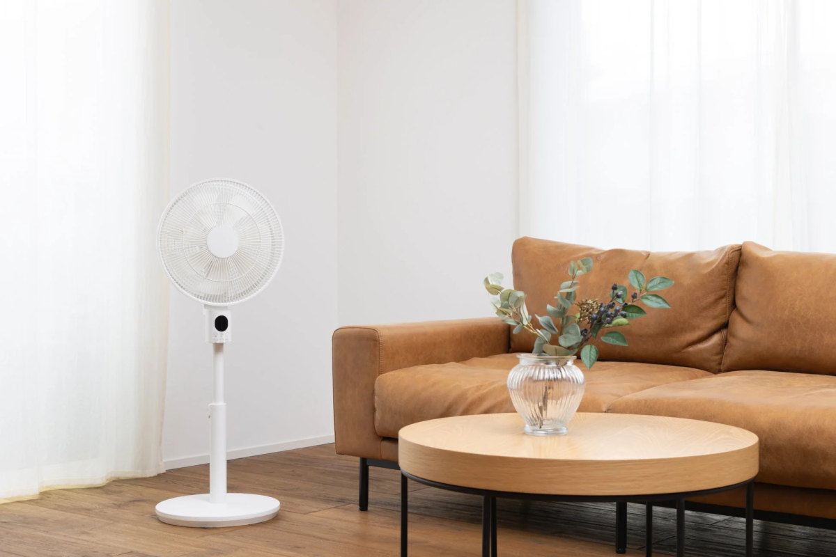 白い扇風機と茶色のソファがあるリビングルーム