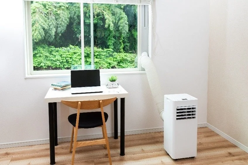 窓から緑が見える部屋に置かれたスポットクーラー