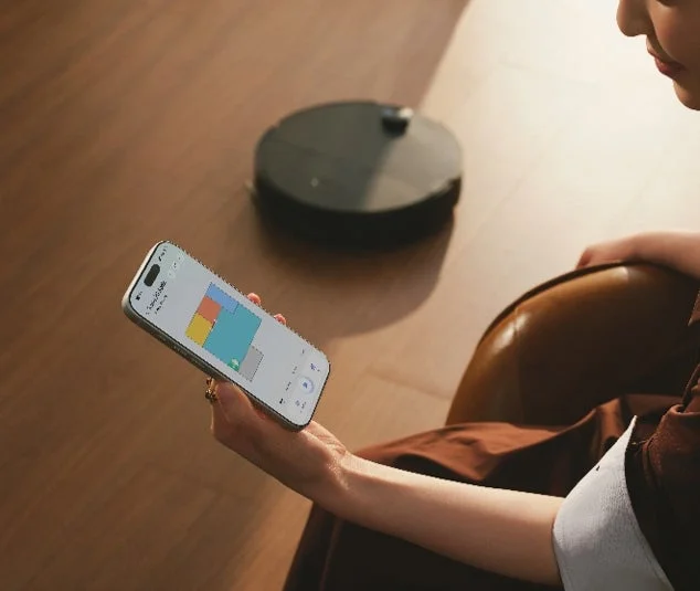 スマートフォンでロボット掃除機を操作する女性