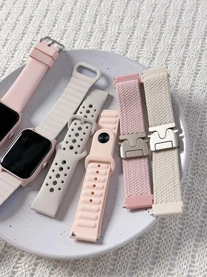 パステルピンクやベージュのスマートウォッチバンドが複数、白い皿の上に置かれています。