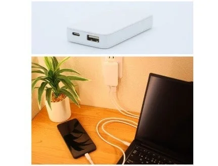 白いモバイルバッテリーのクローズアップと、デスク上でスマートフォンとノートパソコンが充電されている様子を捉えた画像。