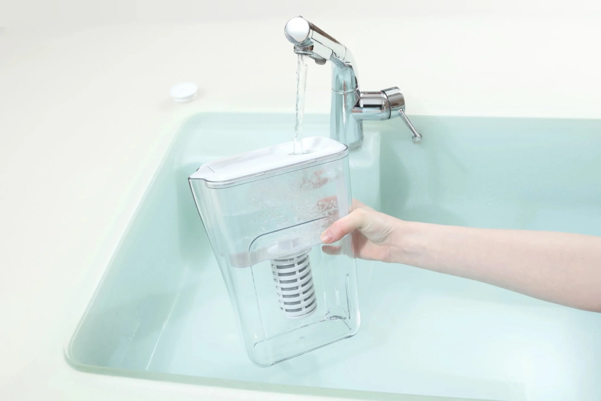 透明な浄水器のピッチャーに、蛇口から水が勢いよく注がれている様子
