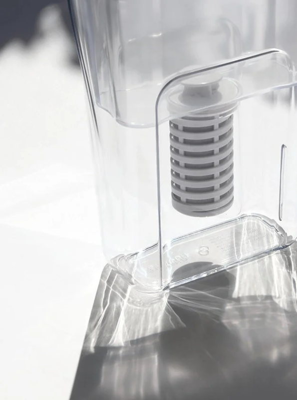透明なプラスチック製浄水器のクローズアップ。内部にはグレーのフィルターカートリッジが見えます