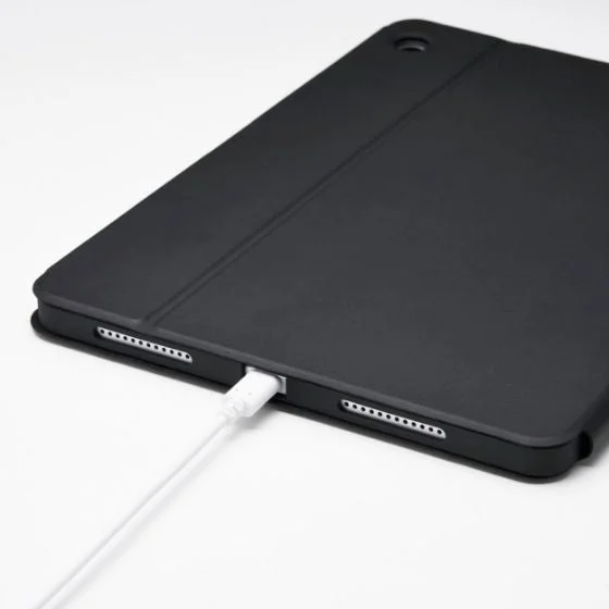 黒いケースに収納されたタブレットが、白いUSB-Cケーブルで充電されている様子
