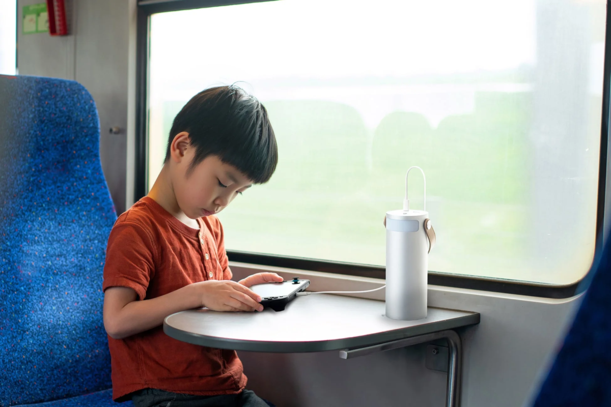 電車内でゲーム機を充電する少年