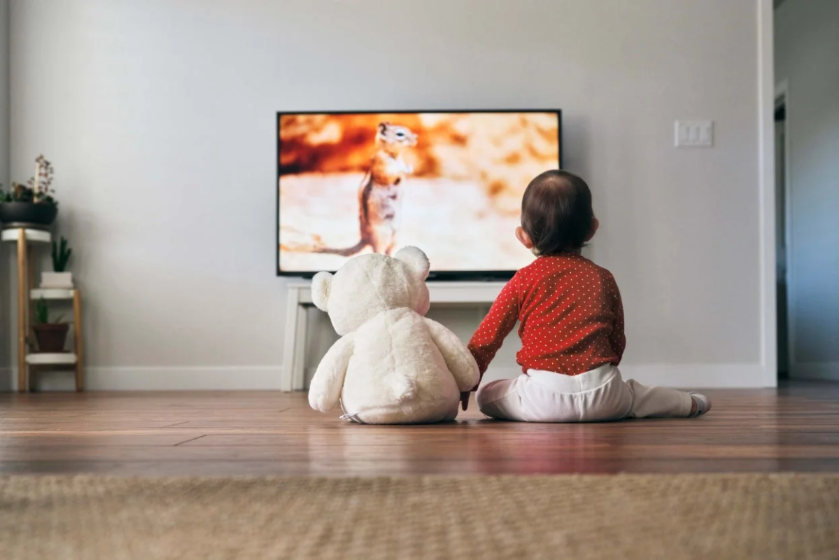 赤ちゃんがテディベアとテレビを見ている画像