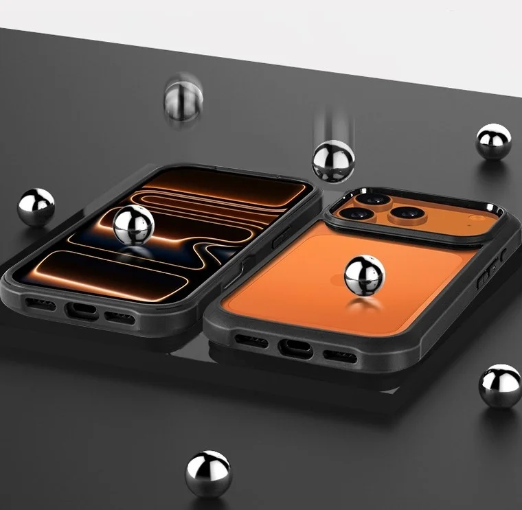 黒い保護ケースに収められた2台のスマートフォンが、暗く反射する表面に置かれ、周囲には複数のメタリックボールが散らばっています。