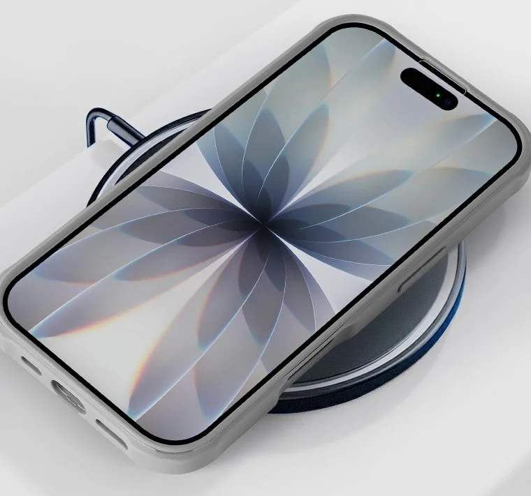 ライトグレーのスマホケースに入ったスマートフォンが、ワイヤレス充電器またはマグネットスタンドの上に置かれている。