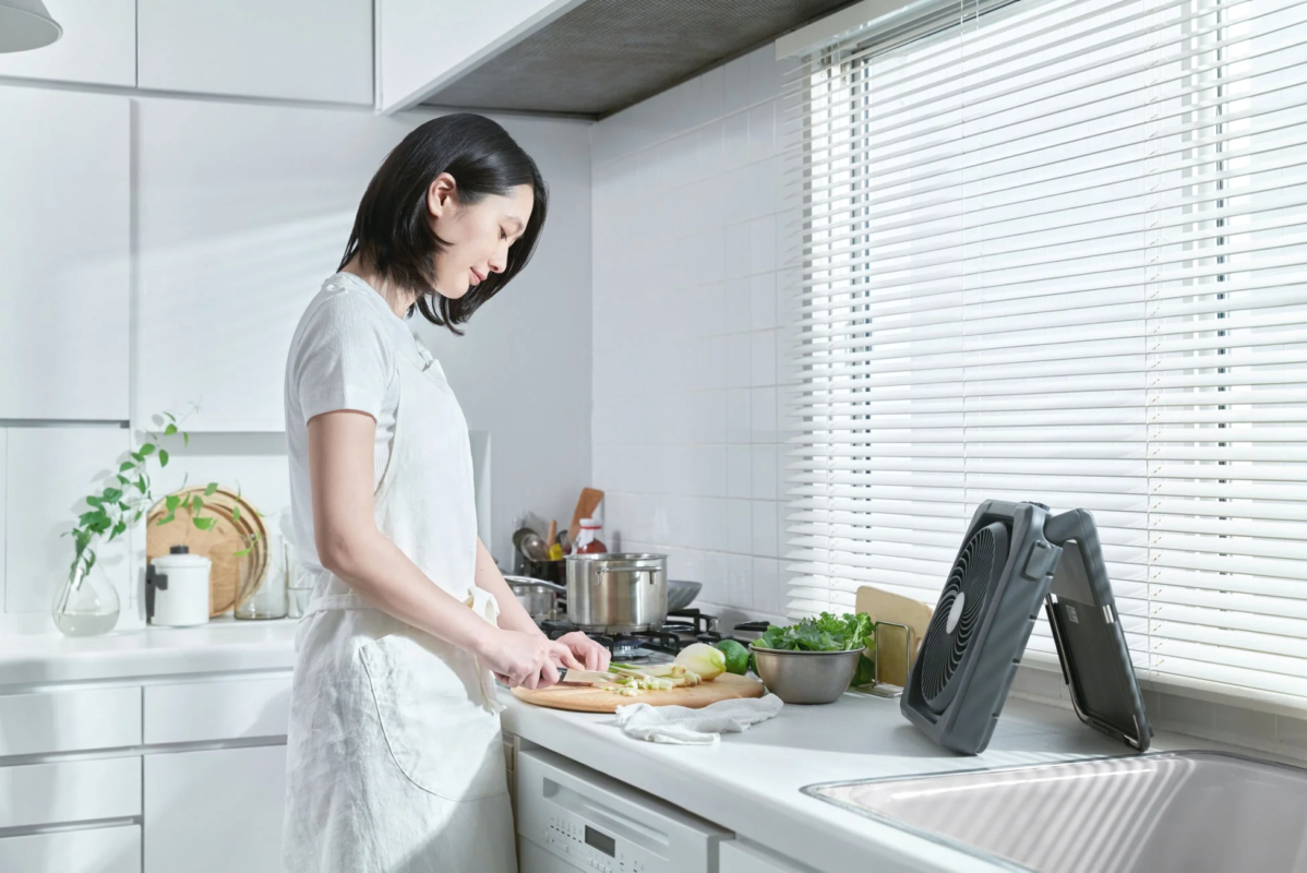 キッチンで料理する女性と扇風機