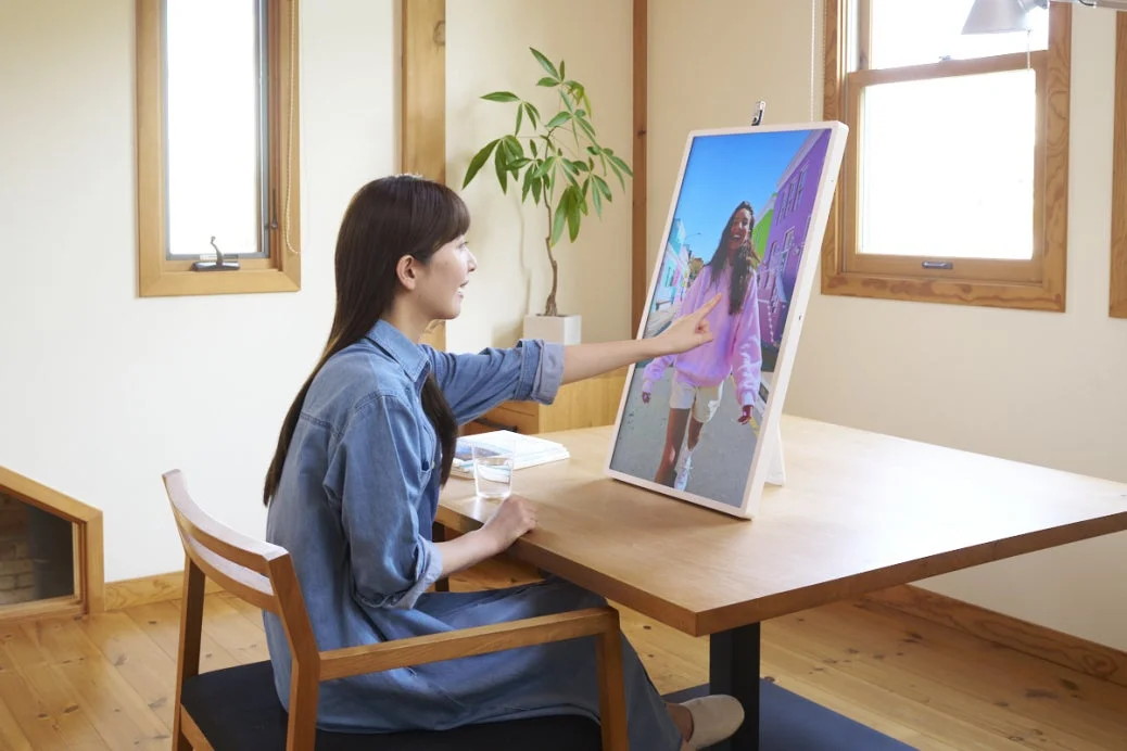 女性がディスプレイに映る画像に触れている様子