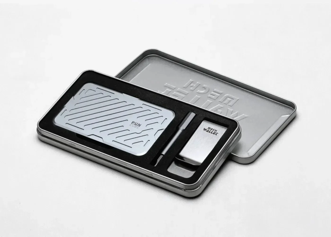銀色の金属製ケースに収められた、メカニカルなデザインのガジェットセット。PUN CUBEのカードケース、MECH WALLET、そしてペンが含まれており、洗練されたギフトアイテムとして適しています。