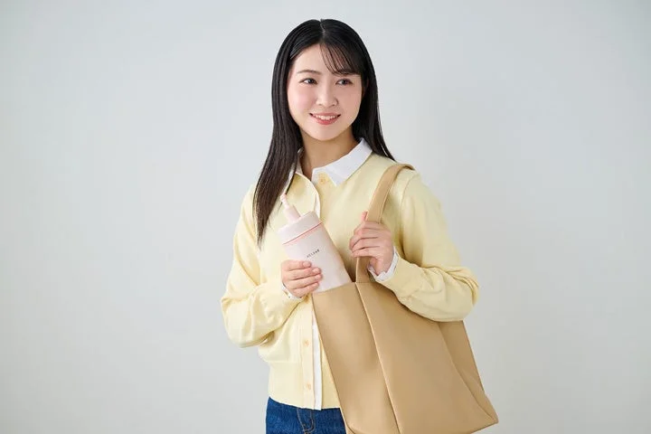 笑顔の女性がボトルをトートバッグに入れる様子